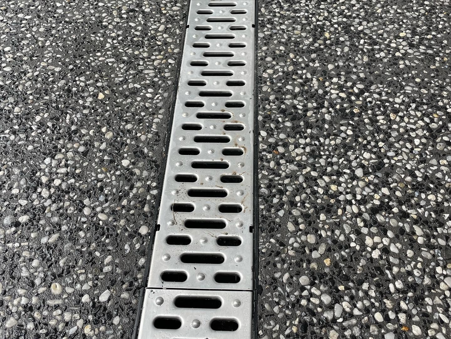 Cowra white and basalt exposed driveway with a grated drain