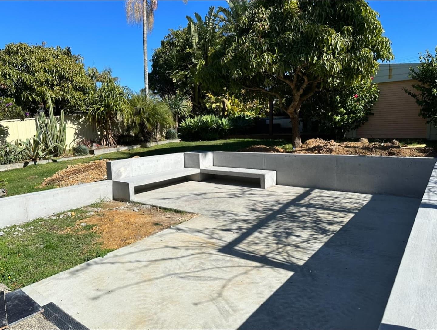 Off-form concrete retaining wall and bench seats around a fire-pit area