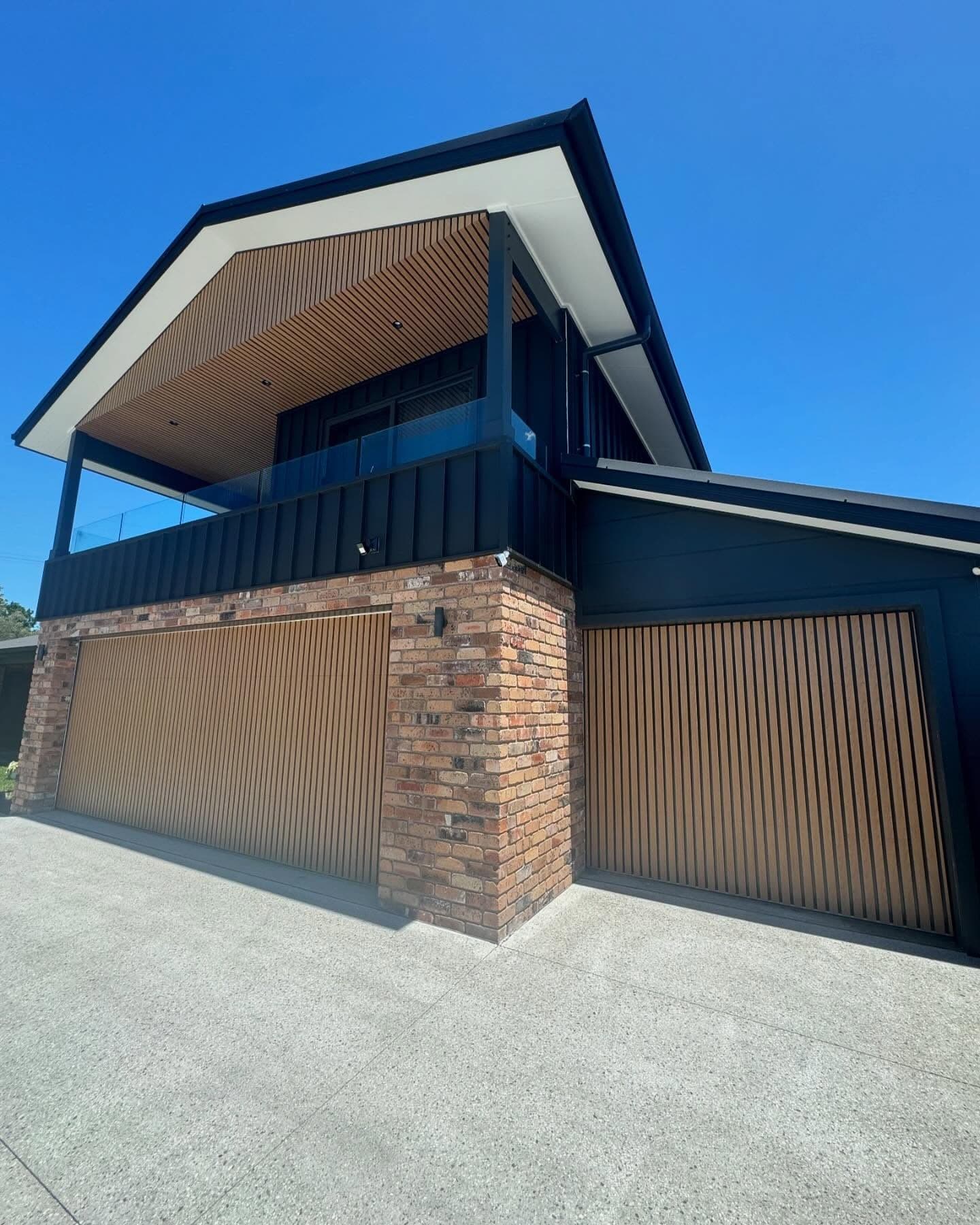 Black-clad house with an exposed-aggregate driveway, Norah Head