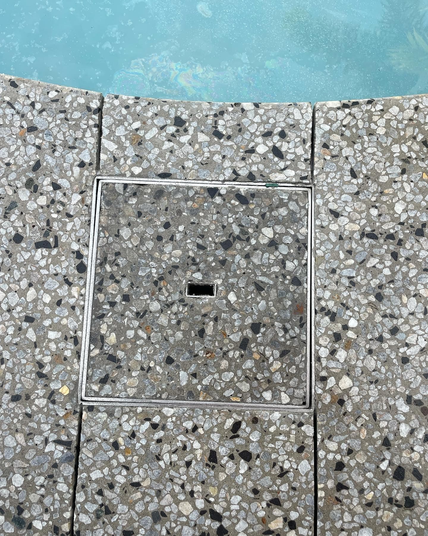 Stainless skimmer lid flush in the honed surround