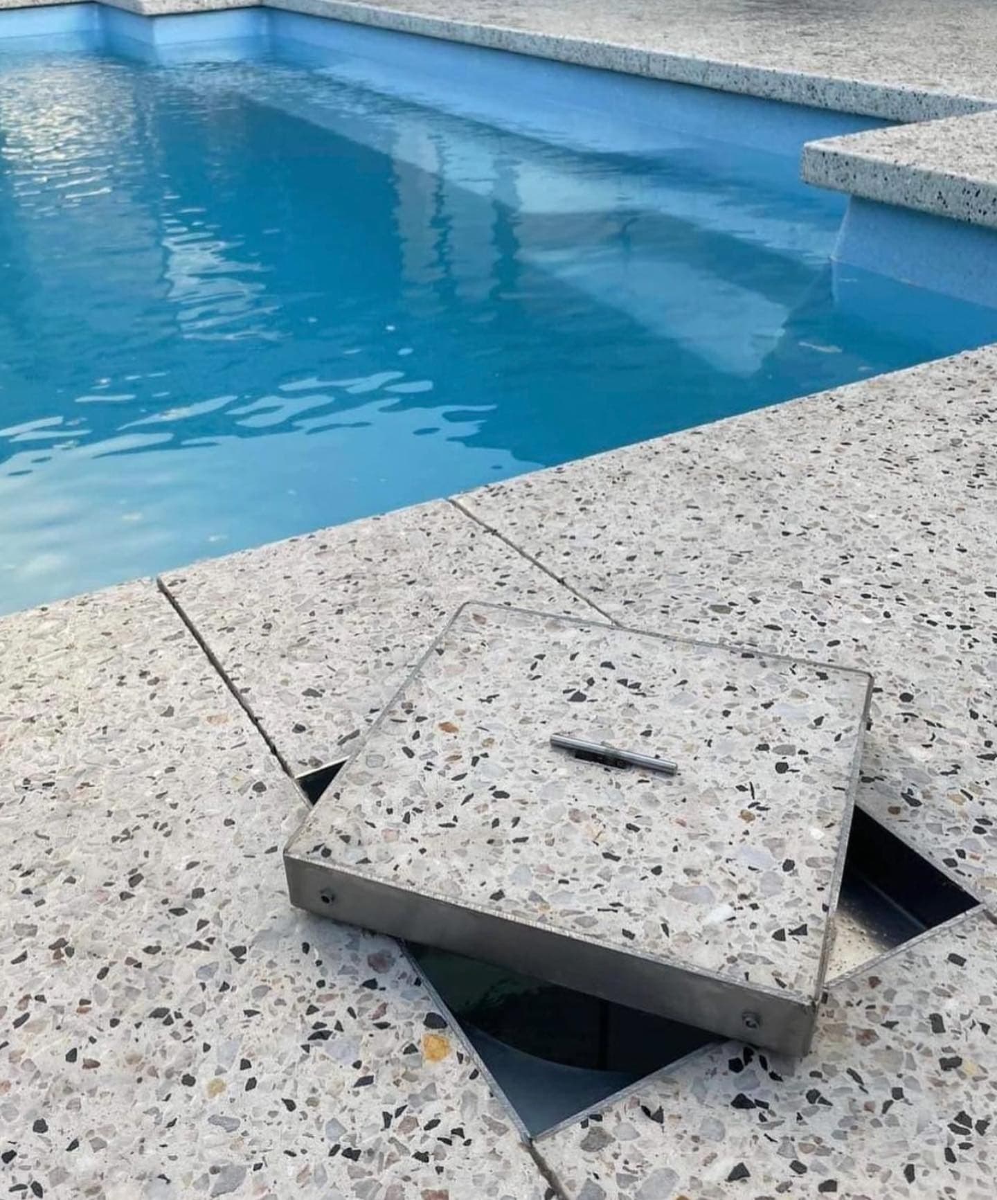 A stainless skimmer lid fitted in exposed aggregate