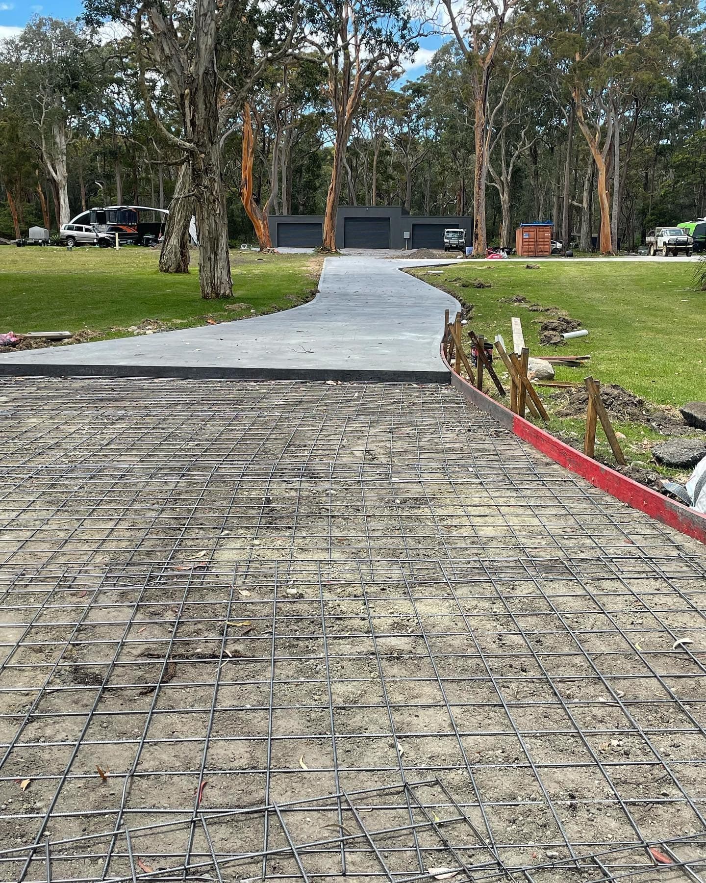 Freshly poured acreage driveway running between timber formwork pegs, East Edge Concreting